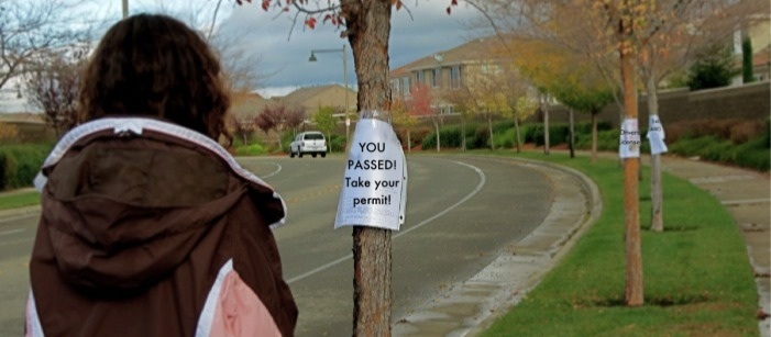 Megan Bauer walking towards the driver's permit sign representing how a permit is the start of a whole new world. Photo by Ariella Appleby taken on Dec. 1.