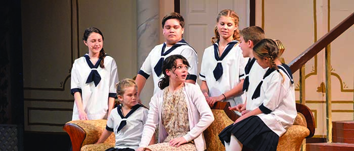 Maria Rainer (Sidney Raey-Gonzales) talks to the Von Trapp children of the maroon cast during the opening performance of the Sound of Music on Feb. 28. Photo by Chelsey Burgess