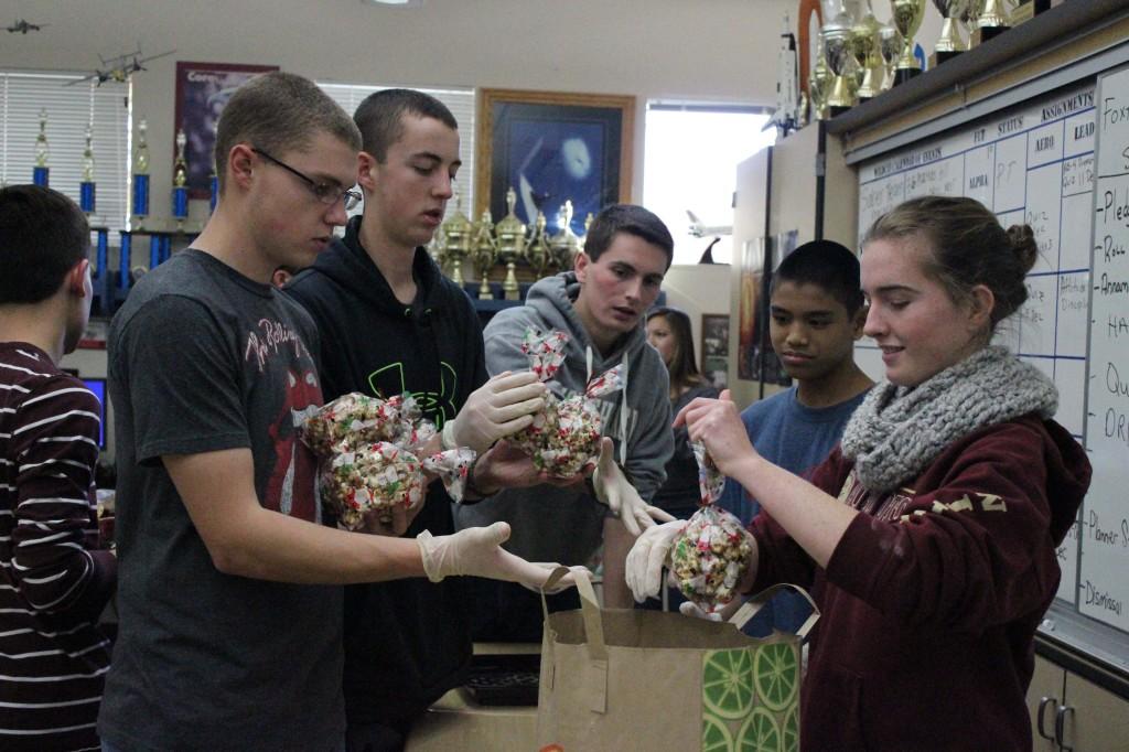 Sophomore Elise Chatterton hands out saran wrap so that ROTC students can wrap the baskets. Photo by THERESA KIM.