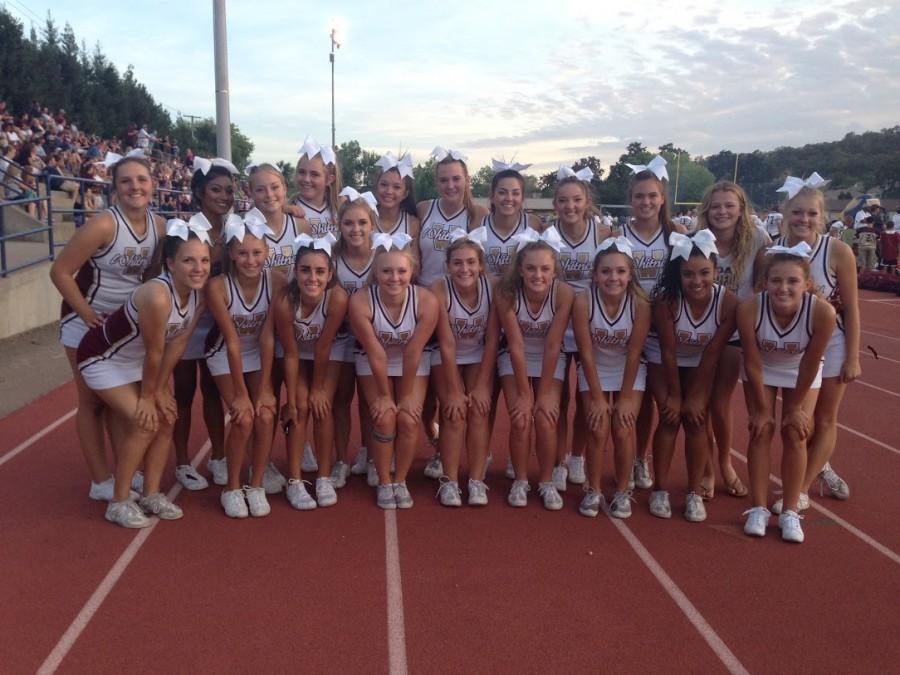 Cheerleaders smile for a picture at a football game. Photo by Nicole Ferguson
