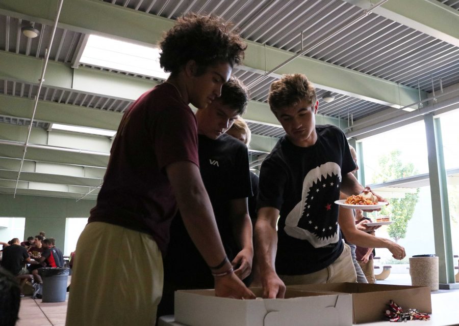 Varsity football players Nick Eaton, Michael Hamp and Justin Kraft grab food at the team dinner the night before the Quarry Bowl. Photo by Morgan Hawkins