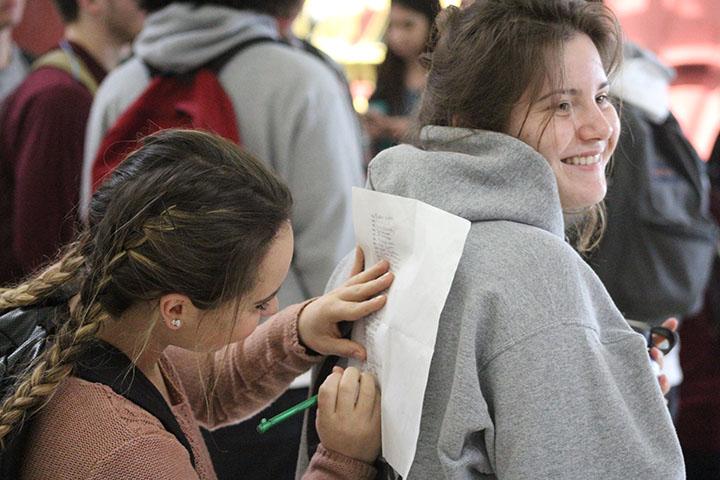 In the cafeteria during lunch, Elizabeth Salvato signs the petition on Carina Pasquale’s back. Photo by Britney Flint.
