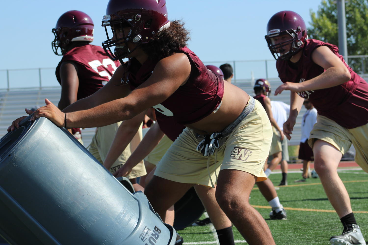 During varsity football practice on July 31, Nick Eaton practices a tackling drill with a trash can. Photo by Madilyn Sindelar.
