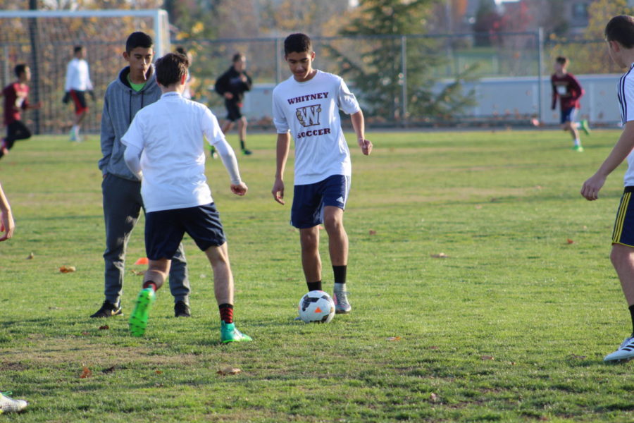 As a part of a keep away-drill used to improve passing skills, Miguel Saavedra dribbles around Nate Sherwood during practice Dec. 18. Photo by Blake Wong.
