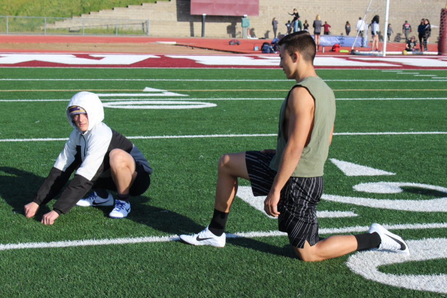 Before+doing+sprints+at+practice+Feb.+27+Wyatt+Lawson+does+lunges+with+teammate+Joey+Souto+to+stretch+out+their+hamstrings.+Photo+by+Alianna+Aviles.