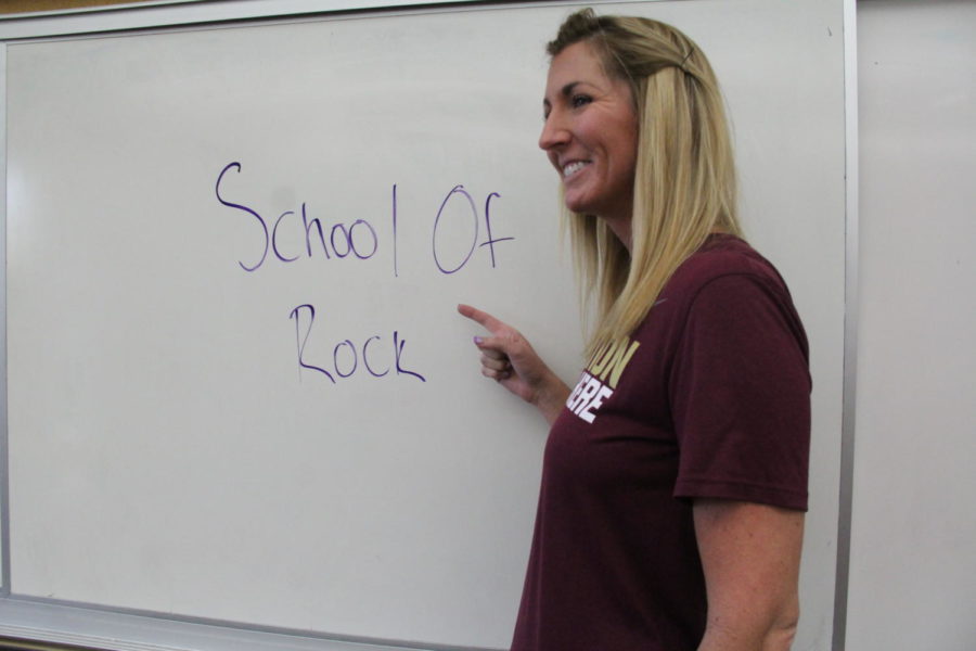 World History and Geography teacher Ms. Suzie Main points to her white board with the words School Of Rock on it. Showing that teachers as well find inspiration from music.