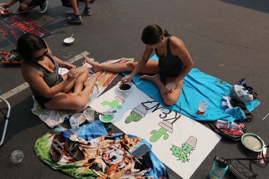 Finishing up her senior parking spot, Makenzie Garman and her sister Midori Garman paint on the finishing touches to their design. In order to avoid the heat, they also used blankets. 