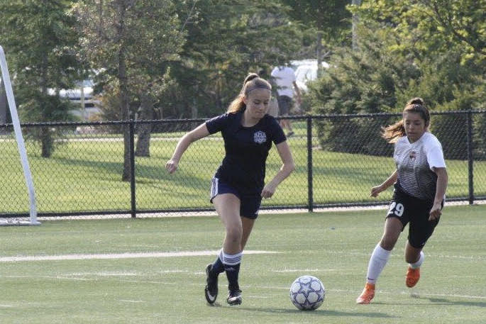 During a club soccer game, Sophia Perkins dribbles while a player from the opposing team challenges her. Photo by Steve Perkins.
