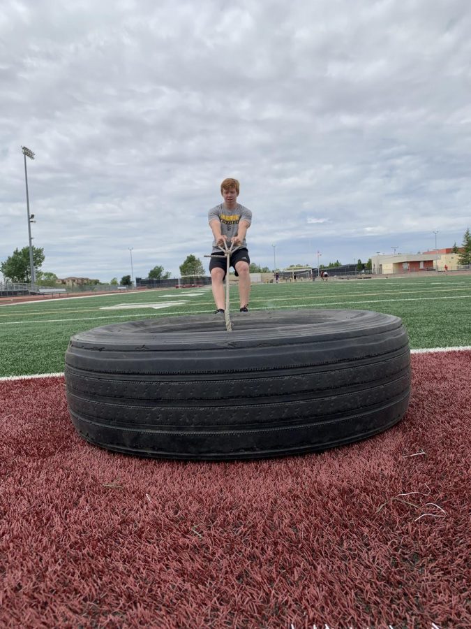 During his workout, May 11, Chris Buck pulls a tire across the football field. Photo by Trinity Barker.