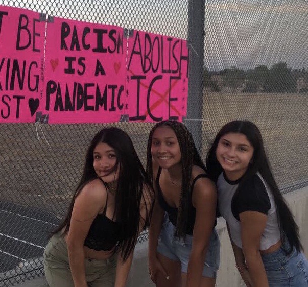 Fabiola Alvarez, Sierra Gladden and Kira Thompson hang anti-racism signs on the Interstate 65 overpass off of Pleasant Grove to support and raise awareness for the BLM movement (image cropped to avoid profanity). Photo by Angela Roberson.