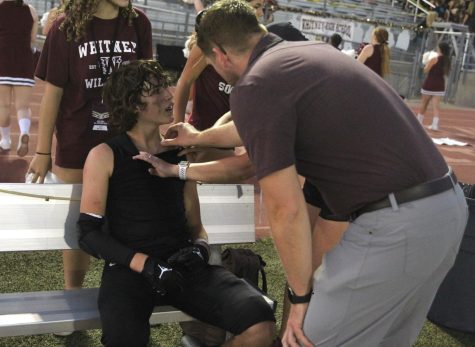 During the football game against Woodcreek on Aug. 25, JV football player Gavin Barnett gets his collarbone checked by Sports Med. students and volunteers on the field to confirm it has been broken for a fourth time. Photo by Julia Leveron Hidalgo.