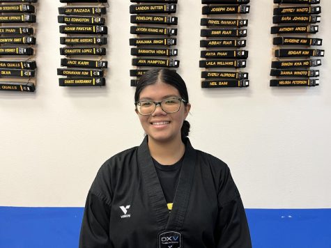 Samantha Veiga stands in front of a wall that represents the Black Belt Club, which is located at her studio, Legend Martial Arts. Photo by Rachel Bustos
