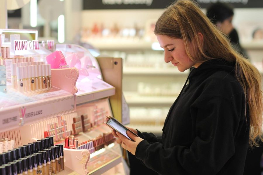 Shopping at Sephora, Sophia Sauer decides between the waterproof or regular Too Faced mascara. After viewing an Alix Earle “Get Ready With Me,” Sauer went to buy the same mascara she uses to replicate the star’s eyelashes. Photo by Emerson Kibby.