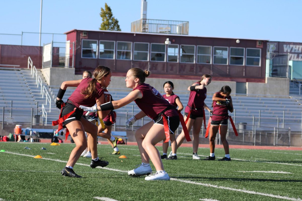 During practice Aug. 25, Emma Rabe reaches for Natalia Takeuchi’s flag in a drill focused on practicing offensive runs to get around a defender. Photo by Riley Rust. 
