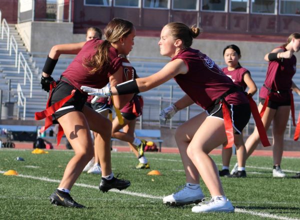 During practice Aug. 25, Emma Rabe reaches for Natalia Takeuchi’s flag in a drill focused on practicing offensive runs to get around a defender. Photo by Riley Rust. 
