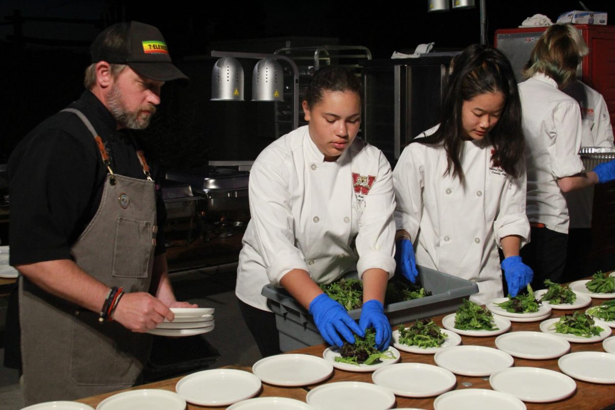 At the start of dinner service, Chef Michael Scagliotti supervises Samira Jackson and Rose Li as they plate greens for the salad course. Scagliotti guided them through the process of making several plates and provided feedback when necessary. Working alongside professionals in the culinary and hospitality industry, Culinary Club members gained experience by preparing several courses for guests at the Starlight Soiree on Oct. 12 at Quarry Park. Photo by Rhaymark Nazareno 