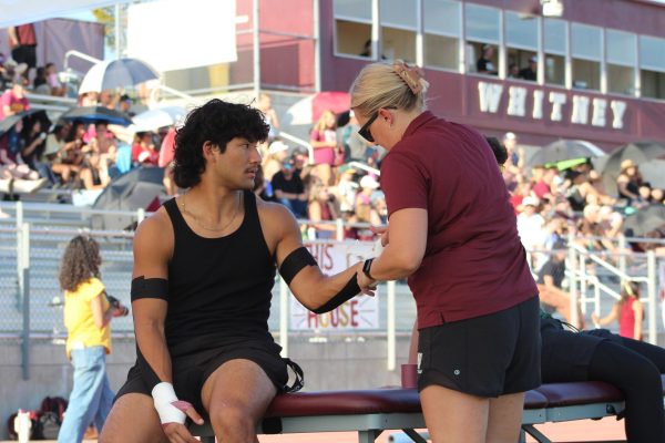 Before the varsity football game against Woodcreek Aug. 29, Jason Taormino gets his arm taped by Ms. Rachel Jaeger. Photo by Gabrielle Robinson.
